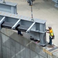 A construction worker eases a huge new steel beam into position as part of construction to replace the westbound side of the Commonwealth Avenue Bridge. (Robin Lubbock/WBUR)