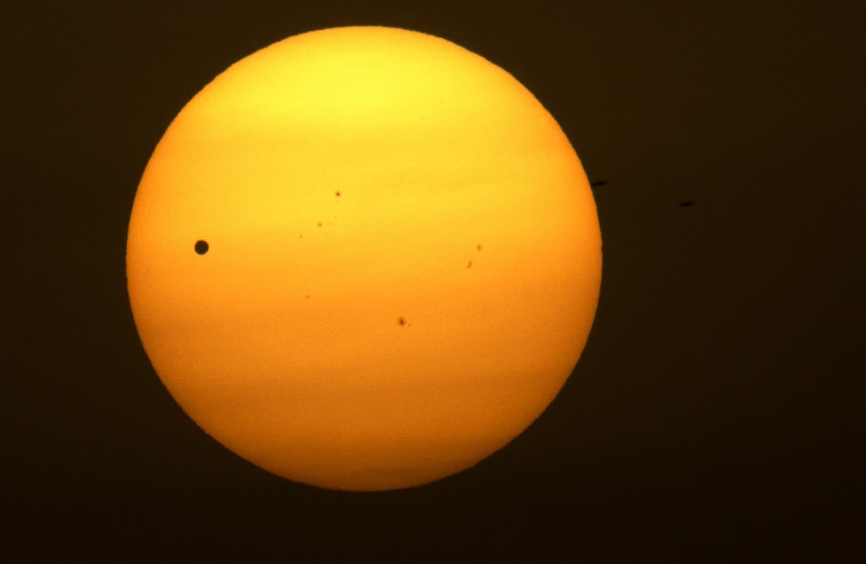 Planet Venus, pictured as a black dot, left, is seen in transit across the sun on the banks of the Ganges River in Varanasi, India, Wednesday, June 6, 2012. (Rajesh Kumar Singh/AP)
