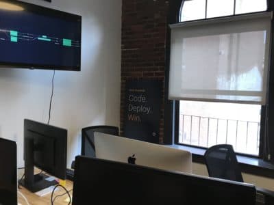 A sign at the Air Force's WeWork outpost reads "Code. Deploy. Win." It's a play on the Air Force motto: "Fly. Fight. Win." (Callum Borchers/WBUR)