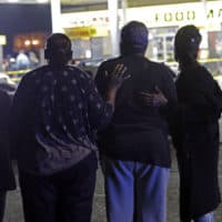 A woman is comforted by others as police investigate the scene of a Mardi Gras day shooting that left at least one dead and others injured, in the lower ninth ward in New Orleans, Tuesday, Feb. 13, 2018. (Gerald Herbert/AP)