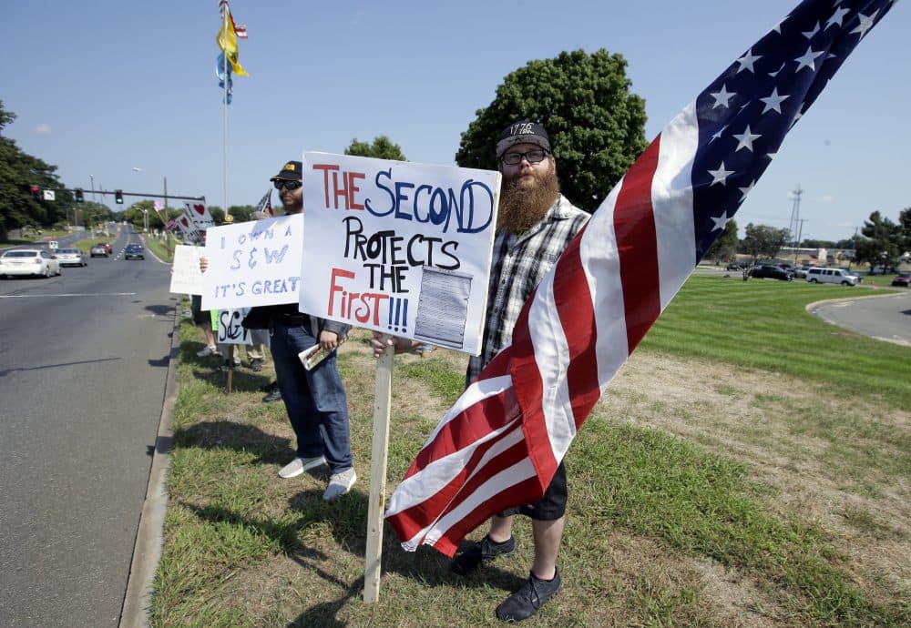 Counter-protester John Allen, of Worcester, center, holds a placard defending Second Amendment rights near the headquarters of gun manufacturer Smith & Wesson on Sunday. (Steven Senne/AP)
