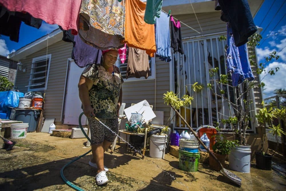 Angelina Arroyo sprays her driveway down during a hot afternoon in Punta Santiago. (Jesse Costa/WBUR)