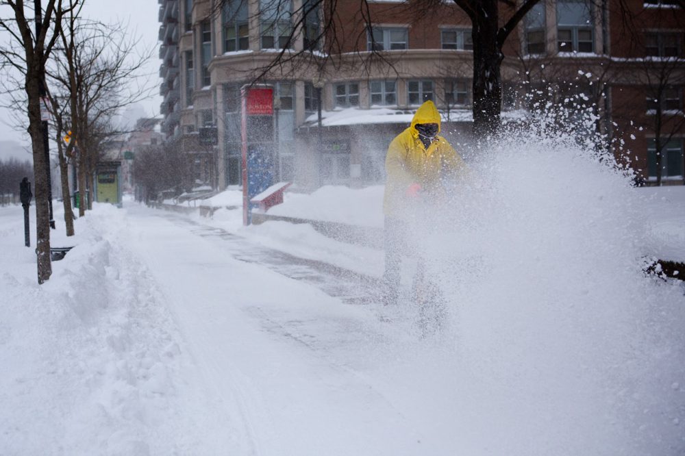 A man uses a snowplow on a sidewalk along Comm Ave in Boston Friday morning.