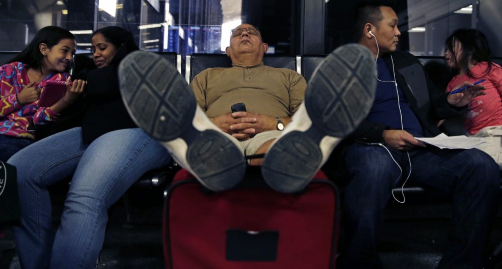 Eli Lopez, of New Bedford, Mass., rests his feet on his luggage while taking a nap after his flight to Puerto Rico was cancelled at Logan Airport Monday. (AP/Charles Krupa)