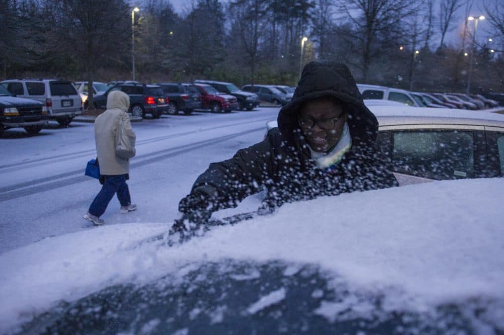 Shmetrice Moore, a nurse at an Emory hospital, scrapes snow and ice off her windshield as she and others are released early from their shift before a winter storm on Wednesday, Feb. 12, 2014, in Johns Creek, Ga. (John Amis/AP)
