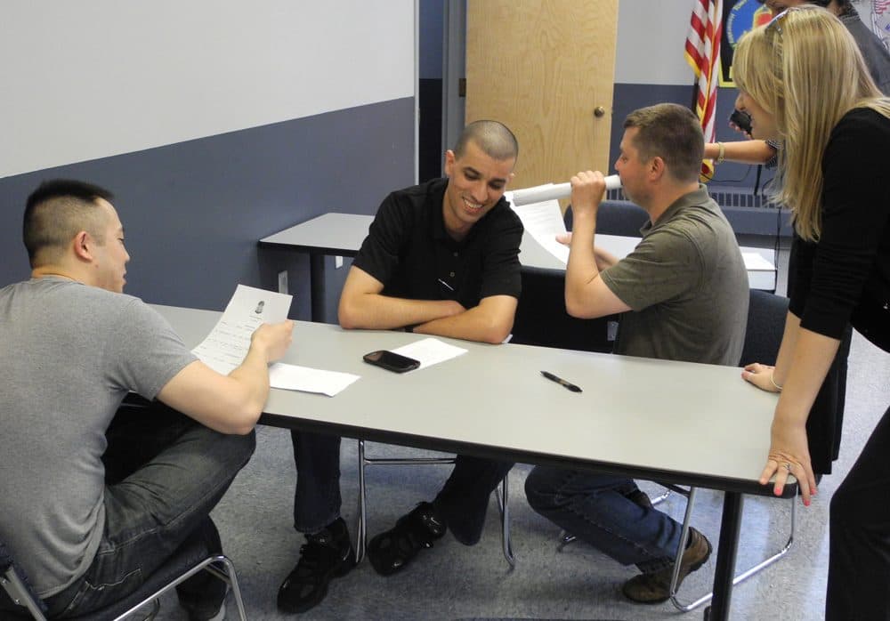 In a training exercise, Somerville Police Officer Eli Kim, left, tries to book Somerville Officer Samir Messaoudi -- playing the role of a man with schizophrenia -- while Cambridge Police Officer Fred Cabral does the sound effects of voices in Messaoudi's head. (Cambridge Police Department)