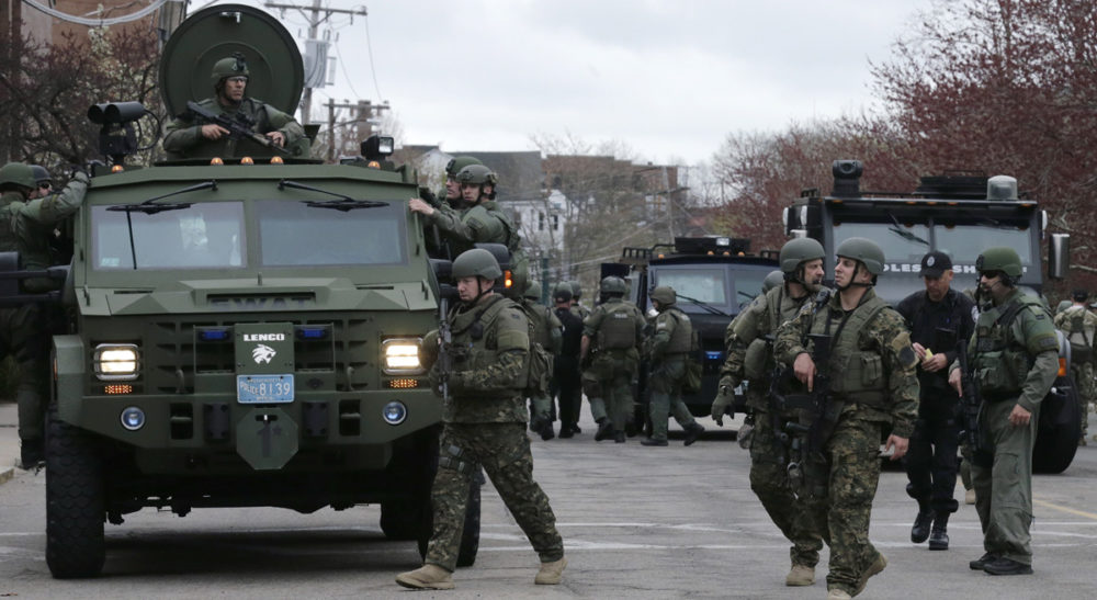 Carol Rose and Kade Crockford: "A thick blue wall of police silence is obstructing the public’s access to timely and accurate data about SWAT deployments." Pictured: A SWAT team unloads from their armored vehicles as they go door to door while searching for a suspect in the Boston Marathon bombings in Watertown, Mass., Friday, April 19, 2013. (Charles Krupa/AP)