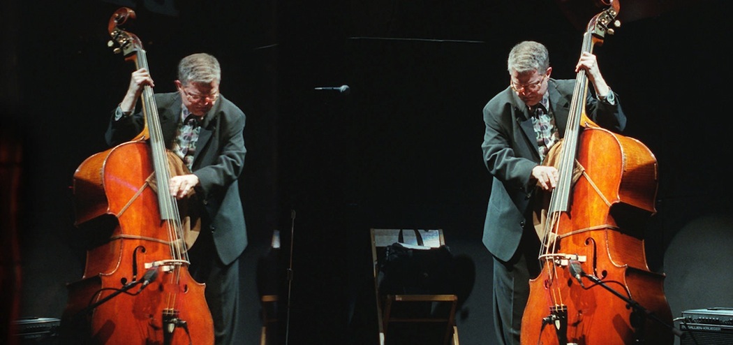 Jazz bassist Charlie Haden is seen in a Plexiglas reflection, left, as he rehearsed during a soundcheck at the House of Blues in West Hollywood, Calif., before a performance by his band Quartet West in 1997. Haden, who suffered from the hearing problems tinnitus -- ringing in the ears -- and hyperacusis -- supersensitivity to loud sounds -- had to play concerts with a Plexiglas shield placed between himself and the drums, piano and saxophone. This reduced the volumeof sound for Haden. (Chris Pizzello/ AP)