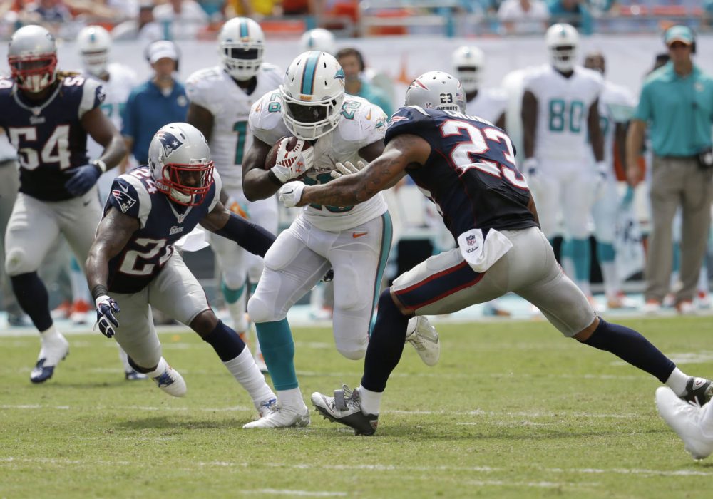 Patriots cornerback Darrelle Revis (24) and free safety Patrick Chung (23) attempt to tackle Miami Dolphins running back Knowshon Moreno (28) during the second half of an NFL football game, in Miami Gardens, Fla., Sunday Sept. 7, 2014. (Lynne Sladky/AP)
