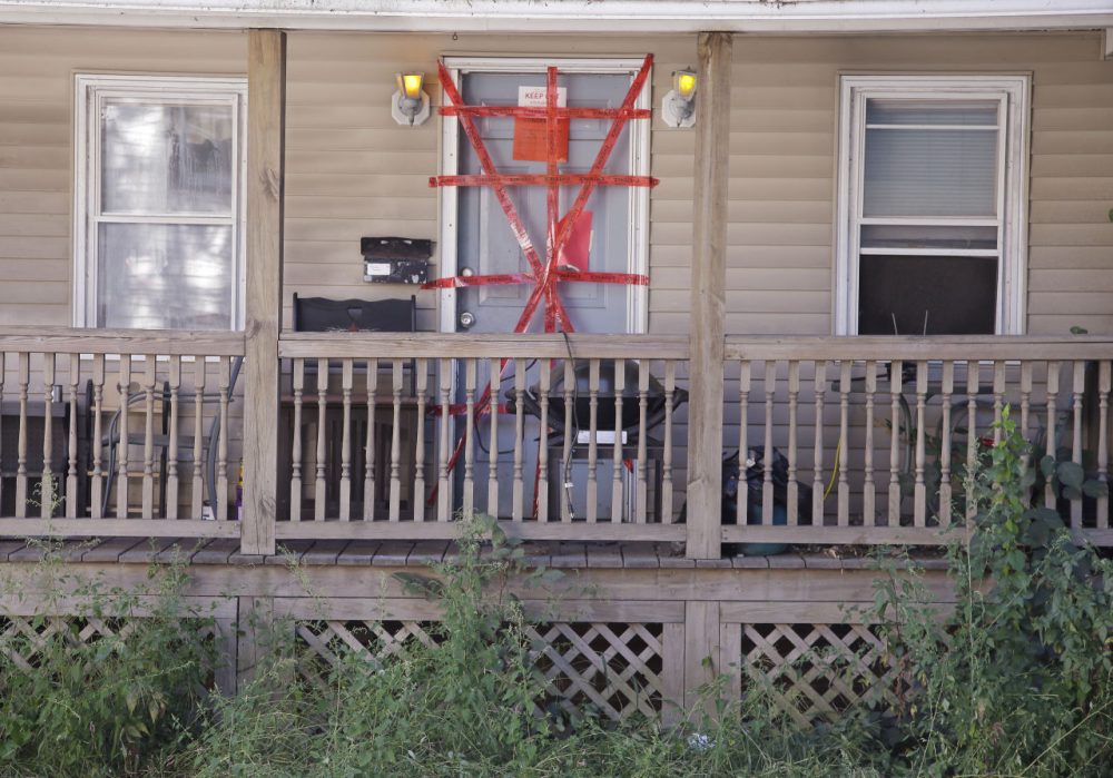 "Condemned" and "keep out" signs are attached behind police tape to the front door of a house where a Massachusetts prosecutor said the bodies of three infants were found Thursday in Blackstone, Mass. (Stephan Savoia/AP)