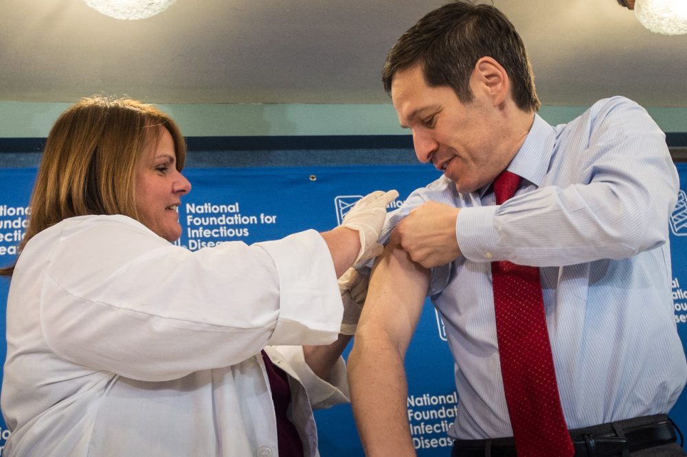 Dr. Thomas Frieden, director of the Centers for Disease Control and Prevention, receives a flu shot from Sharon Bonadies at the conclusion of a news conference at the National Press Club in Washington, Thursday, Sept. 18, 2014. "Vaccination is the single most important step everyone 6 months of age and older can take to protect themselves and their families against influenza," said Frieden. Influenza hospitalized a surprisingly high number of young and middle-aged adults last winter, and this time around the government wants more of them vaccinated. (AP Photo/J. David Ake)