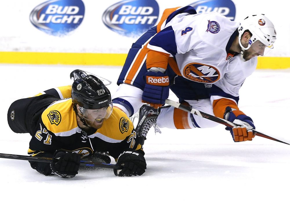 Boston Bruins defenseman Dougie Hamilton (27) slides on the ice after colliding with New York Islanders defenseman T.J. Brennan (4) during the second period of a preseason hockey game in Boston. The Islanders won 5-3. (Elise Amendola/AP)