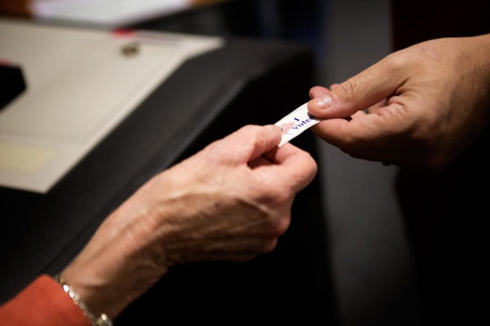 Joanne Kinchla passes out “I Voted” stickers after voters cast ballots at Burlington High School.