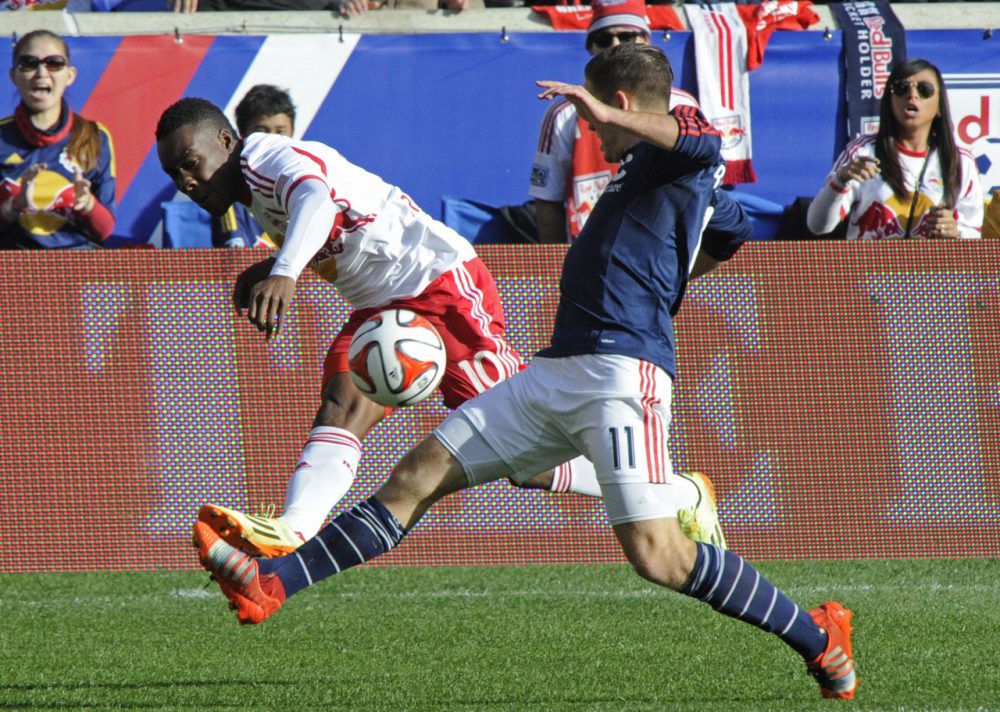 New England Revolution forward Kelyn Rowe, right, blocks a shot by New York Red Bulls midfielder Lloyd Sam during the first half. (Bill Kostroun/AP)