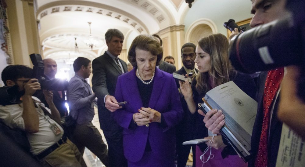 In this photo, Senate Intelligence Committee Chair Sen. Dianne Feinstein, D-Calif. is surrounded by reporters on Capitol Hill in Washington, Tuesday, Dec. 9, 2014, as she leaves the Senate chamber after releasing a report on the CIA's harsh interrogation techniques at secret overseas facilities. Feinstein branded the findings a "stain on the nation's history." (J. Scott Applewhite/AP)