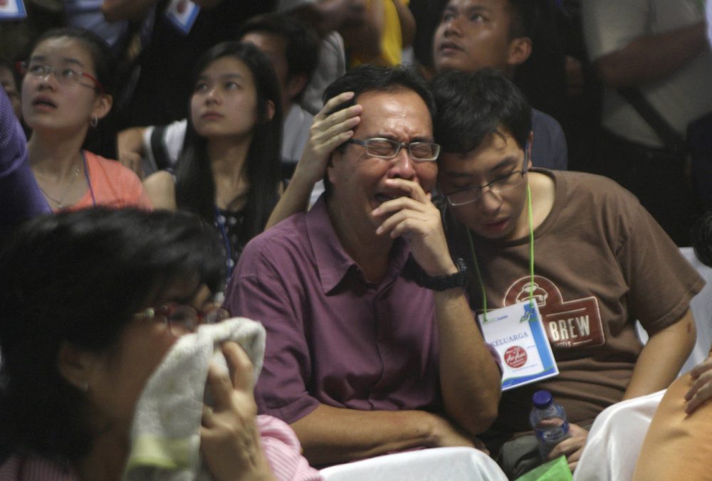 Relatives of passengers of the missing AirAsia Flight 8501 react upon seeing the news on television about the findings of bodies on the waters near the site where the jetliner disappeared. (Trisnadi/AP)