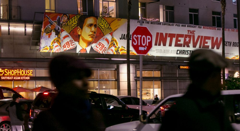 People walk past a banner for "The Interview"at Arclight Cinemas, Wednesday, Dec. 17, 2014, in the Hollywood section of Los Angeles. A U.S. official says North Korea perpetrated the unprecedented act of cyberwarfare against Sony Pictures that exposed tens of thousands of sensitive documents and escalated to threats of terrorist attacks that ultimately drove the studio to cancel all release plans for the film at the heart of the attack, "The Interview." (Damian Dovarganes/AP)