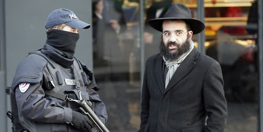 A police officer and a Jewish passerby talk outside the kosher grocery where four people were killed by Amedy Couiibaly. (Francois Mori/AP)