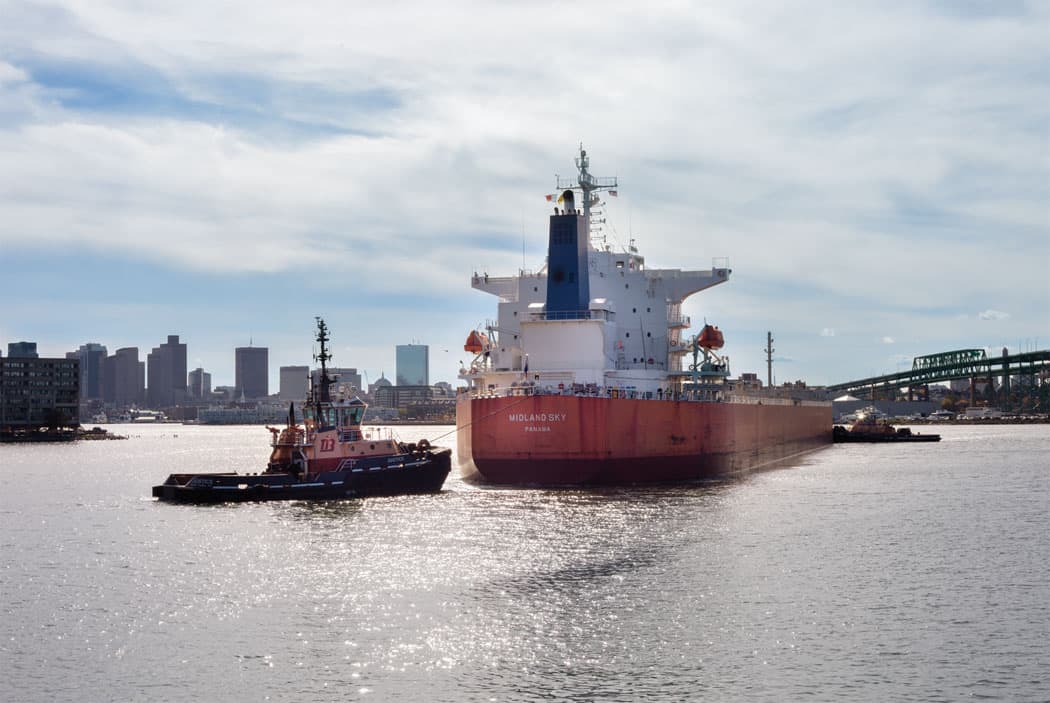 Tugboats help a cargo ship filled with salt navigate the Chelsea River to the Eastern Salt Company in Chelsea last fall. (Allison Cekala)