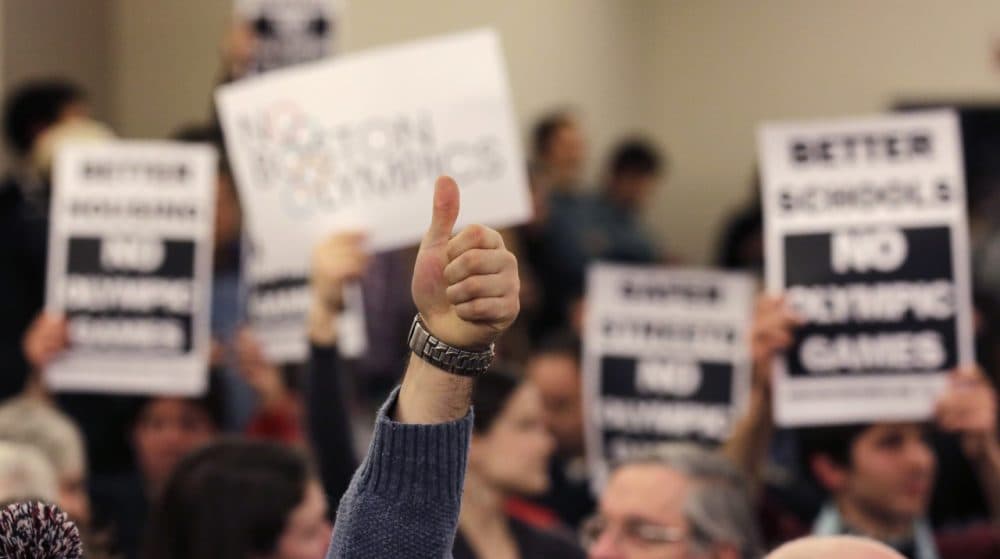 A supporter of the Boston Olympics bid gives a thumbs up in front of a group opposed to the bid, during the first public forum regarding the city's 2024 Olympics bid, on Thursday. (Charles Krupa/AP)