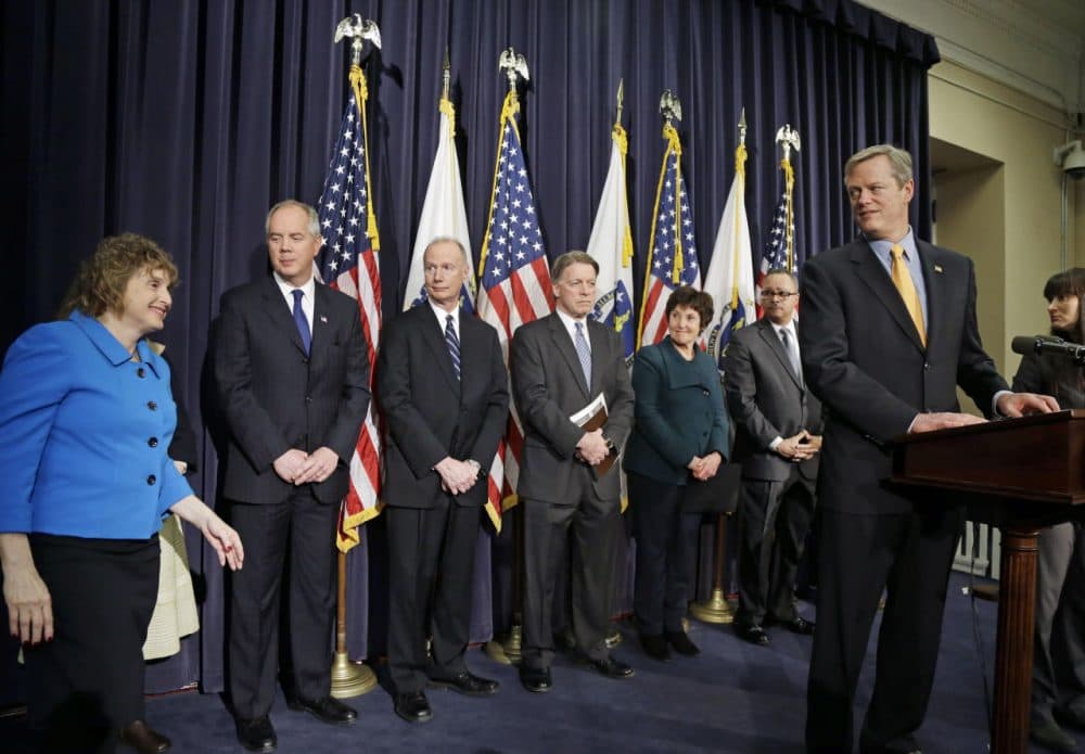 Gov. Charlie Baker, far right, turns to Stephanie Pollack, state secretary of transportation, far left, at a news conference Friday, where he named a seven-member panel of experts in transportation, economic development and municipal planning to come up with a fix for the troubled MBTA. (Elise Amendola/AP)