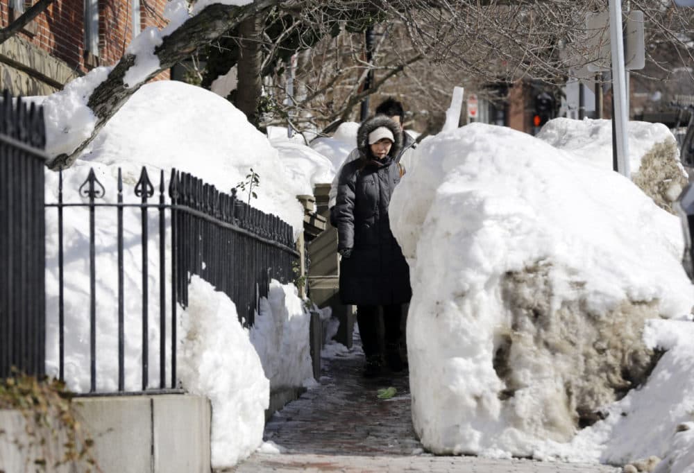 A day before the latest storm hit the area on Saturday, pedestrians walk single file through snow banks on a Beacon Street sidewalk in Boston. (Elise Amendola/AP)