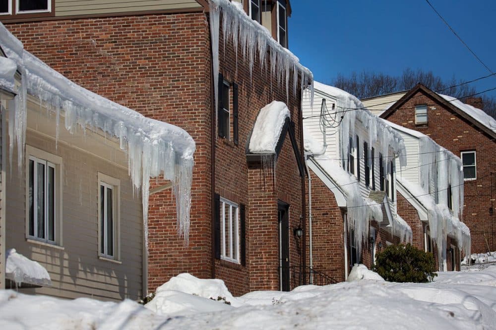 Huge banks of snow hindered many potential homebuyers from getting to know neighborhoods and finding parking spaces around homes for sale. In this photo taken last month, icicles hang from homes buried in snow along Itasca Street in Mattapan. (Jesse Costa/WBUR)