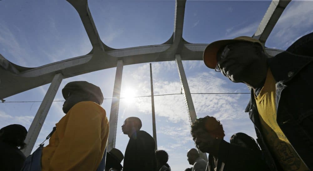 In this photo, crowds of people walk toward Selma after taking a symbolic walk across the Edmund Pettus Bridge, Sunday, March 8, 2015, in Selma, Ala. (Gerald Herbert/AP)