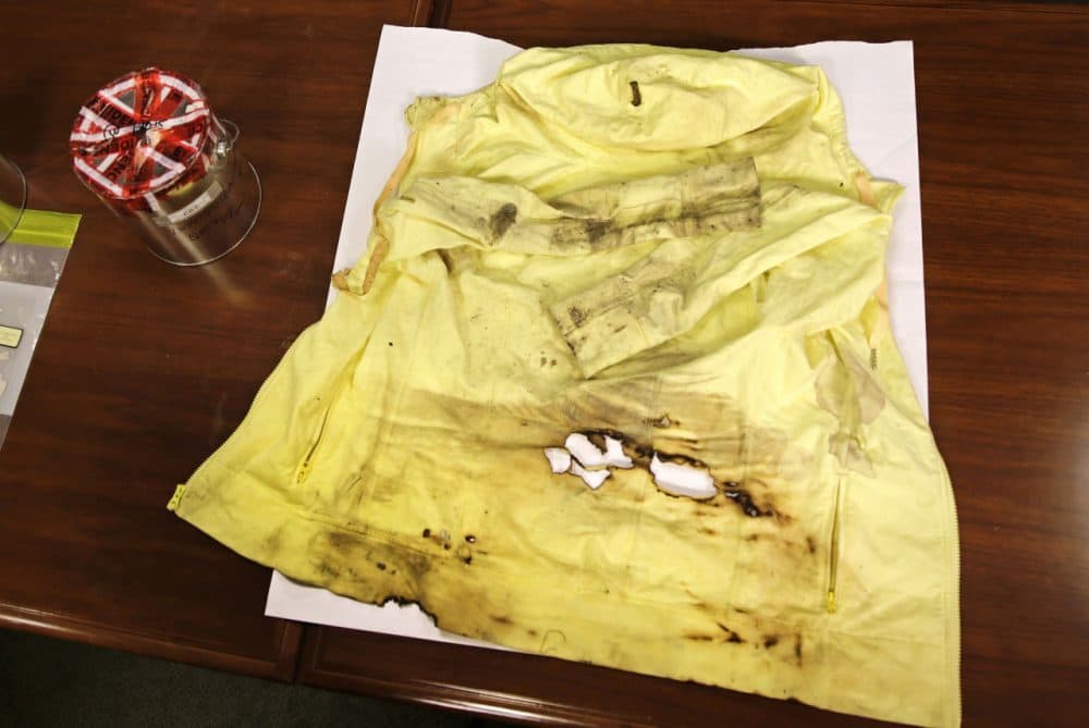 A damaged yellow jacket, worn by Boston Marathon bombing survivor Jessica Kensky during the blast, is displayed to the media alongside a can containing remnants of a bomb. (AP)
