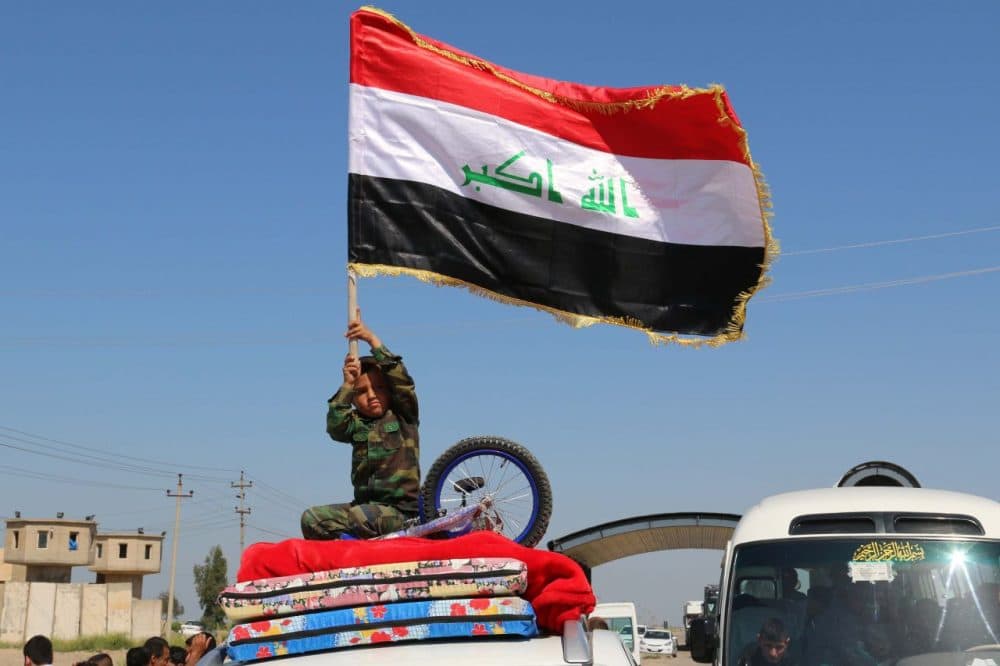 An Iraqi child waves his national flag as displaced families leave Kirkuk on April 2, 2015, to go back to the cities of Tikrit, Samara and al-Alam after they were retaken by security forces and pro-government fighters from the Islamic State group. (Marwan Ibrahim/AFP/Getty Images)
