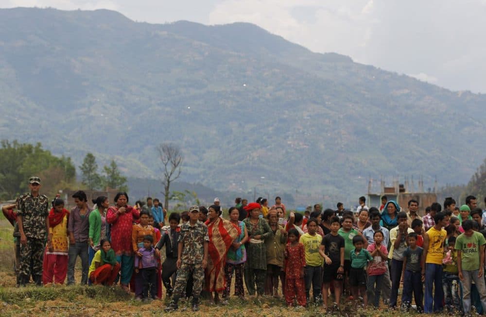 Nepalese villagers watch as relief material is brought in an Indian air force helicopter for victims of Saturday's earthquake at Trishuli Bazar in Nepal, Monday. (Altaf Qadri/AP)