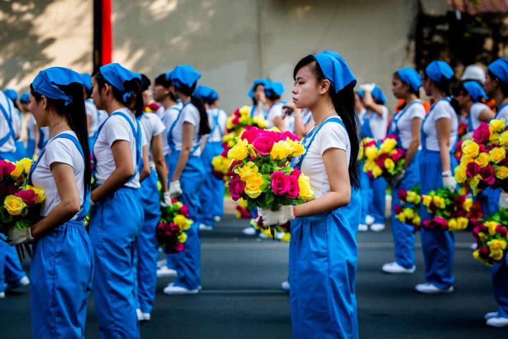 Women march representing the workers in the parade to celebrate 40 years since the Communist victory in Saigon. (Quinn Ryan Mattingly for WBUR)