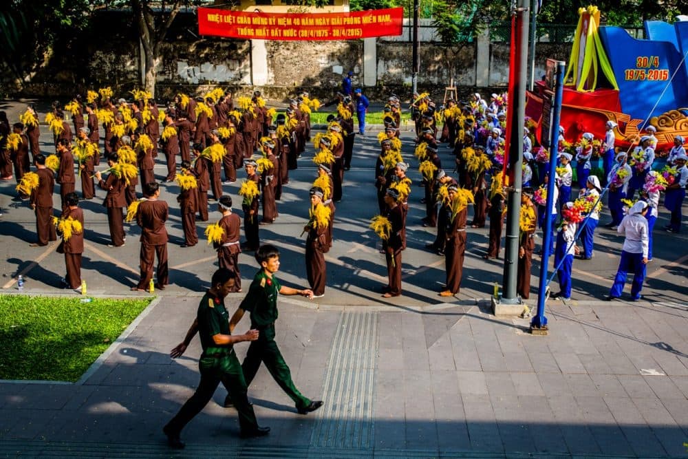 Parade marchers representing workers and farmers wait in formation for the Reunification Day parade to begin, Thursday in Ho Chi Minh City. (Quinn Ryan Mattingly for WBUR)