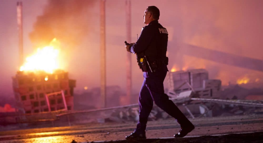 A police officer walks by a blaze, Monday, April 27, 2015, during unrest following the funeral of Freddie Gray in Baltimore. Gray died from spinal injuries about a week after he was arrested and transported in a Baltimore Police Department van. (Matt Rourke/AP)