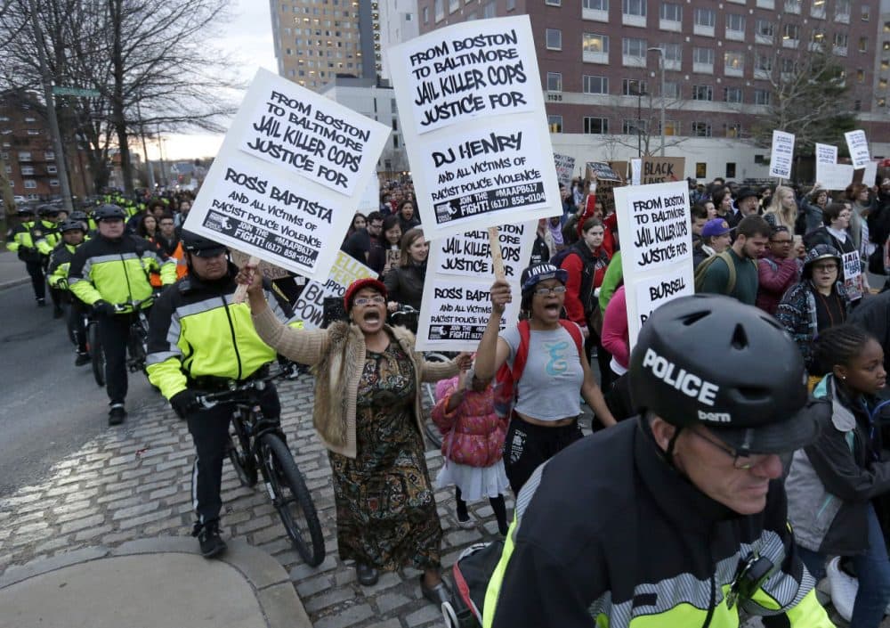 Demonstrators display placards and chant slogans as they are escorted by police during a march near Boston Police headquarters Wednesday evening. (Steven Senne/AP)