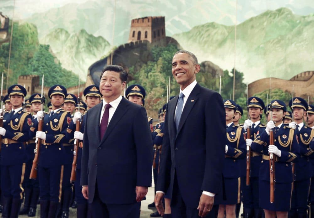 President Obama smiles as a group of children wave flags and flowers during a welcome ceremony held by Chinese President Xi Jinping on Nov. 12, 2014. (Andy Wong/AP)