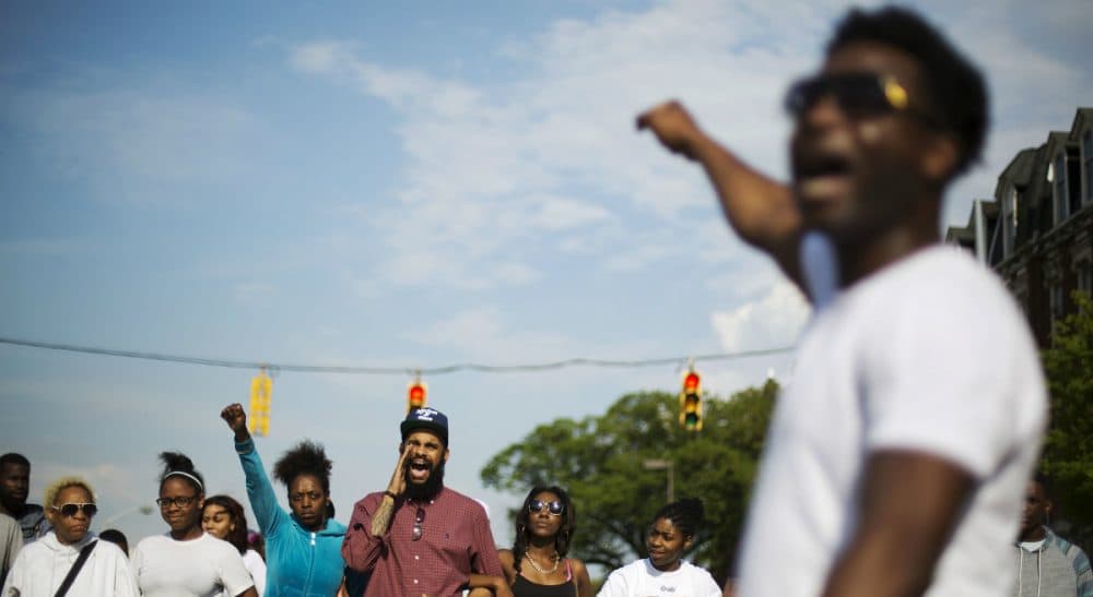 Real talk about what's happening in Baltimore -- and why it's different from what we're seeing on TV. In this photo, protesters link arms while marching toward City Hall to demonstrate the death of Freddie Gray, Thursday, April 30, 2015, in Baltimore. (David Goldman/AP)
