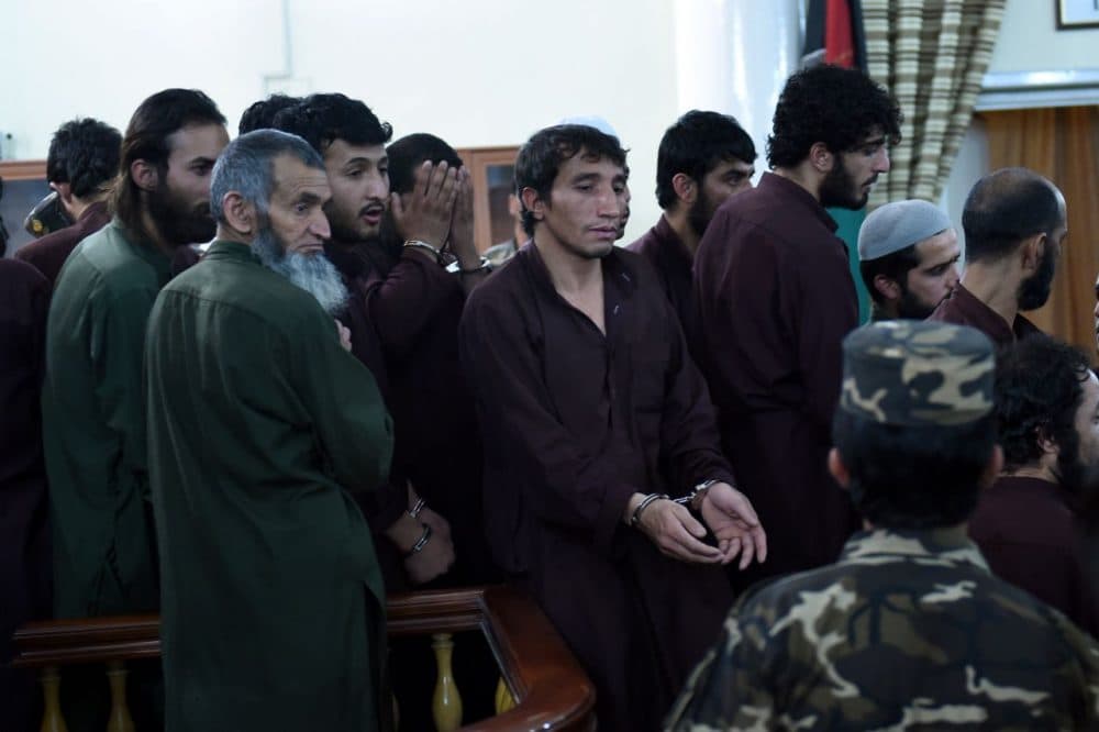 An Afghan security personnel escorts suspects at close of daily proceedings at the Primary Court trial in Kabul on May 2, 2015. The first trial of 49 suspects, including 19 police officers, on charges relating to the mob killing of an Afghan woman began in Kabul on May 2 and is expected to continue for two days. The suspects all face charges relating to the March 19 killing of a 27-year-old woman, Farkhunda. (Wakil Kohsar/AFP/Getty Images)