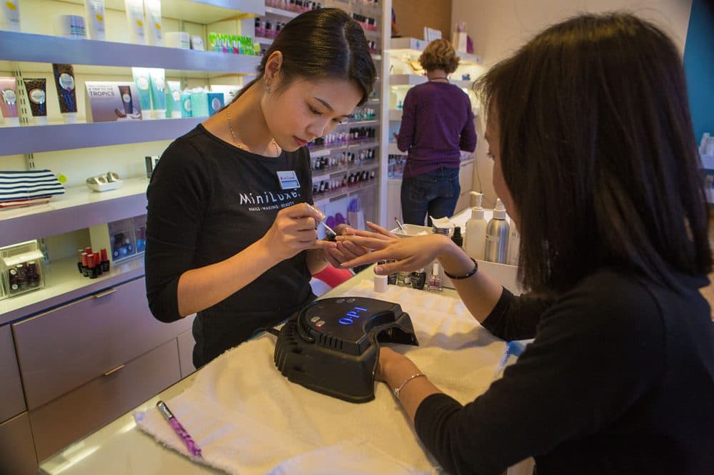 A MiniLuxe nail technician works on a client's nails in the company's Brookline location. (Jesse Costa/WBUR)