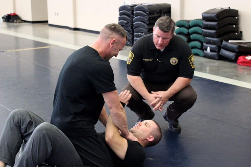 Scott Kendrick observes two Canadian County deputies during defensive tactic training at CLEET headquarters in Ada, Oklahoma. (Kate Carlton Greer/KGOU)