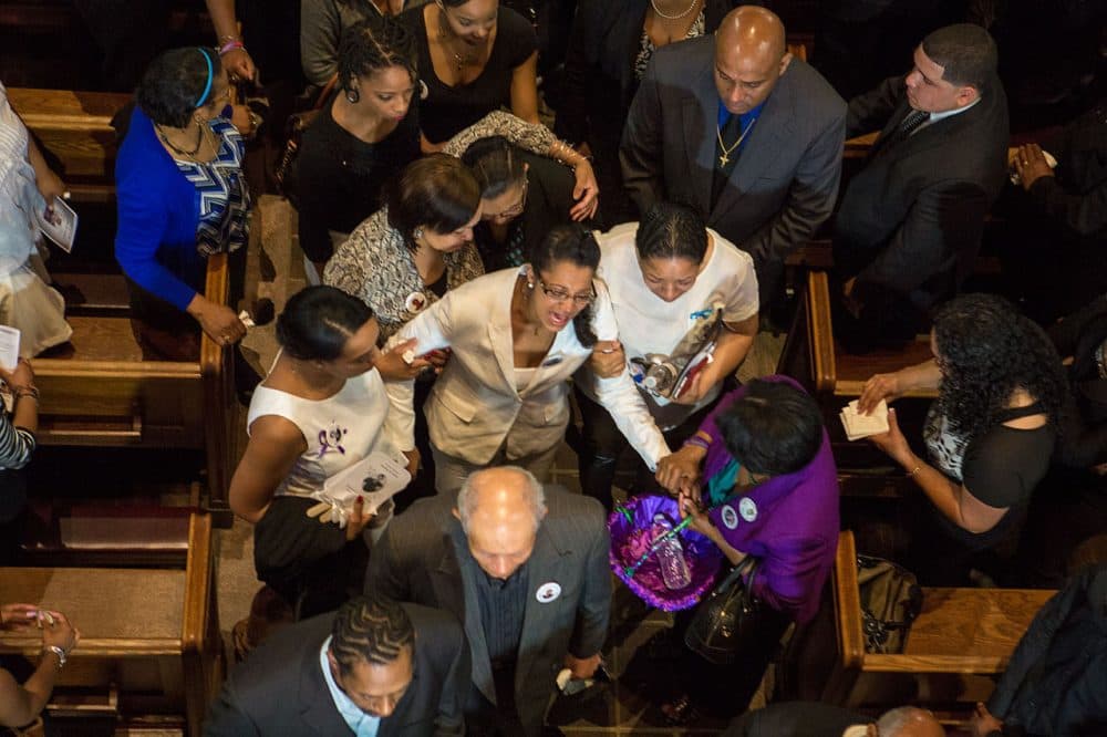 Friends and relatives comfort Laura Fatima Dos Santos as her son's casket is ushered out of St Peter’s Parish Church. (Jesse Costa/WBUR)