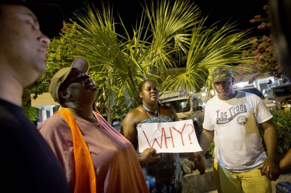 Surreace Cox of North Charleston, S.C., holds a sign during a prayer vigil down the street from the Emanuel AME Church early Thursday following a shooting Wednesday night that killed nine people. (David Goldman/AP)