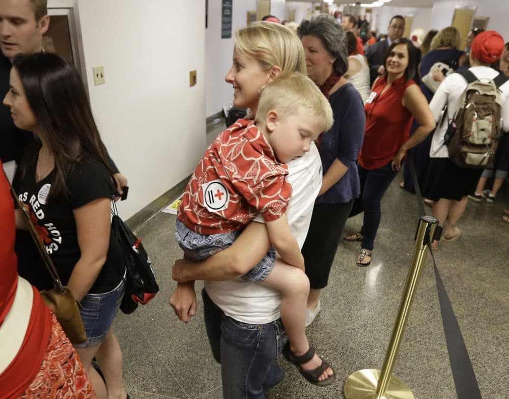 Christy Pritchard carries her son, Zachary, 3, as she waits to appear before the Assembly Health Committee to voice her opposition to a measure mandating that schoolchildren be vaccinated at the Capitol in Sacramento, Calif., Tuesday, June 9, 2015. (Rich Pedroncelli/AP)