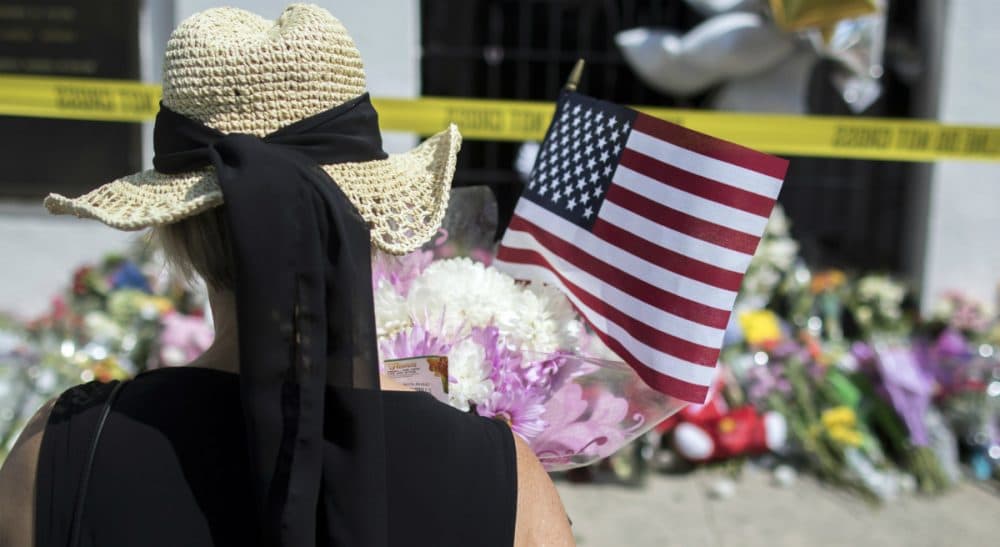 A woman pauses before laying a bouquet of flowers and an American flag at a memorial, Friday, June 19, 2015 in front of the Emanuel AME Church in Charleston, S.C. (Stephen B. Morton/AP)