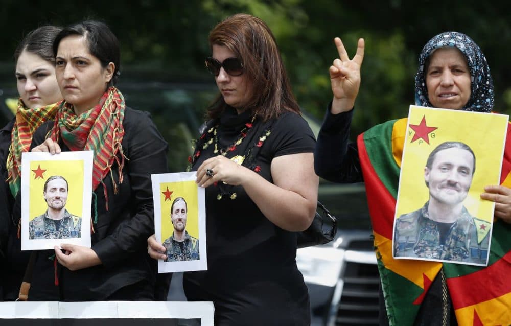 People from the New England Kurdish Association hold pictures of Keith Broomfield outside the Grace Baptist Church in Hudson, Massachusetts, following his funeral service Wednesday. Broomfield was killed in Syria while fighting the Islamic State group alongside Kurdish forces. (Michael Dwyer/AP)