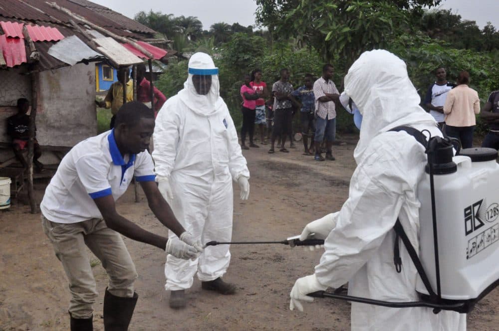 Health workers wash their hands after taking a blood specimen from a child to test for the Ebola virus in an area where a 17-year old boy died from the virus on the outskirts of Monrovia, Liberia, Tuesday, June 30, 2015. Liberian authorities on Tuesday quarantined the area where the corpse of the boy was found, sparking fears this West African country could face another outbreak of the disease nearly two months after being declared Ebola-free. (Abbas Dulleh/AP)