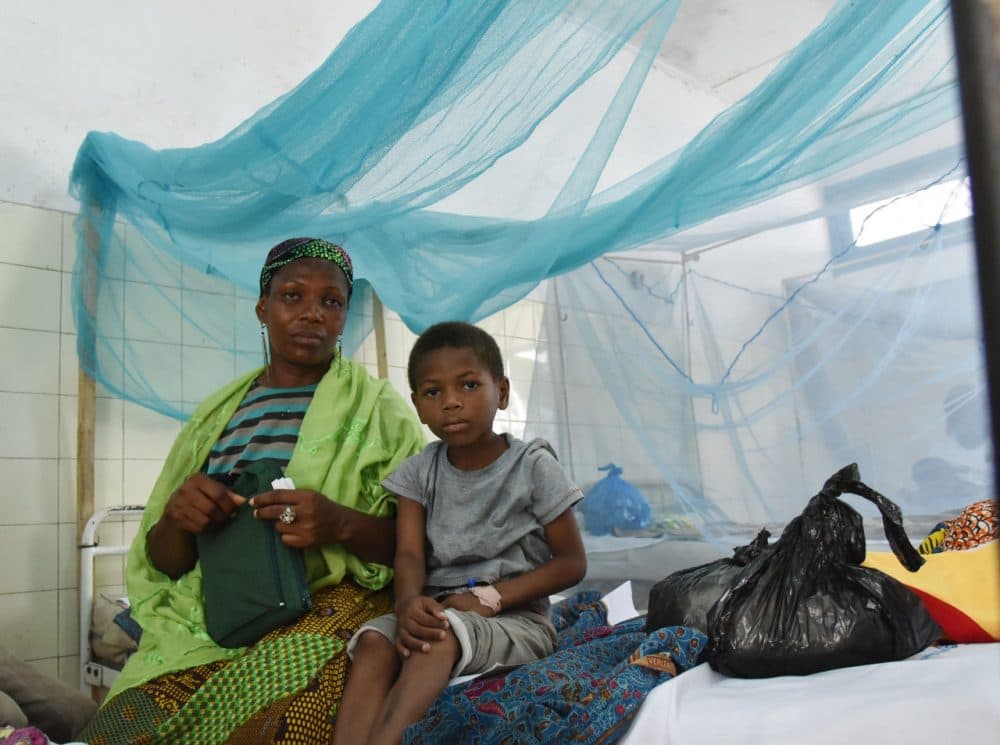 A mother sits with her sick child in a bed with mosquito net in a hospital on April 24, 2015 in the popular suburb of Port-Bouet in Abidjan, on the eve of the World Malaria Day on April 25, 2015. (Sia Kambou/AFP/Getty Images)