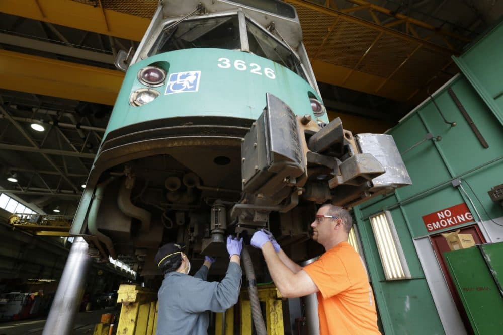 Light rail repairer Rob Cunningham, of Belchertown, Mass., right, works on the coupling of a railcar at the Massachusetts Bay Transportation Authority's Riverside maintenance facility in Newton, Mass. (Steven Senne/AP)