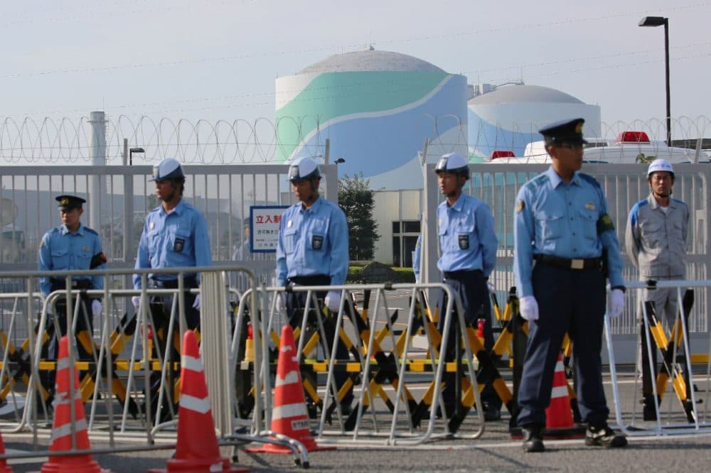 Police officers and security personnel stand in front of the gate of the Kyushu Electric Power Sendai nuclear power plant as anti-nuclear protesters rally against the restarting of the nuclear reactor in Satsumasendai, Kagoshima prefecture, on Japan's southern island of Kyushu yesterday. Japan restarted a mothballed nuclear reactor for the first time in two years since the Fukushima meltdown. (Jiji Press/Getty Images)