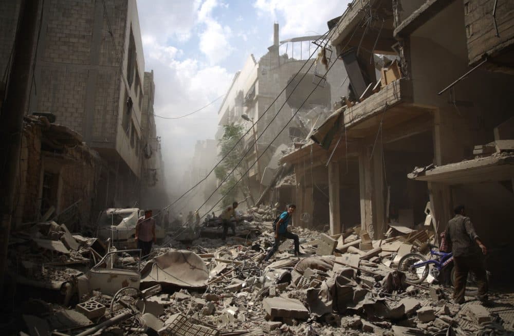 Syrians walk amid the rubble of destroyed buildings following reported air strikes by regime forces in the rebel-held area of Douma, east of the capital Damascus, on August 30, 2015. More than 240,000 people have been killed since Syria's conflict began in March 2011, and half of the country's population has been displaced by the war. (ABD Doumany/Getty Images)